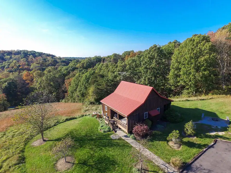 One of the best Airbnbs in Ohio is this red roofed-brown cabin sitting high atop a hill in Hocking Hills with a fantastic view