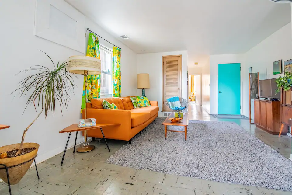 Colorful midcentury apartment with orange couch and teal blue door. It is one of the best Airbnbs in Columbus, Ohio
