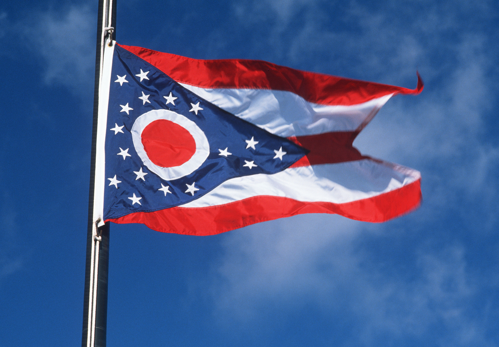 Ohio flag waving in wind with bright blue sky in background