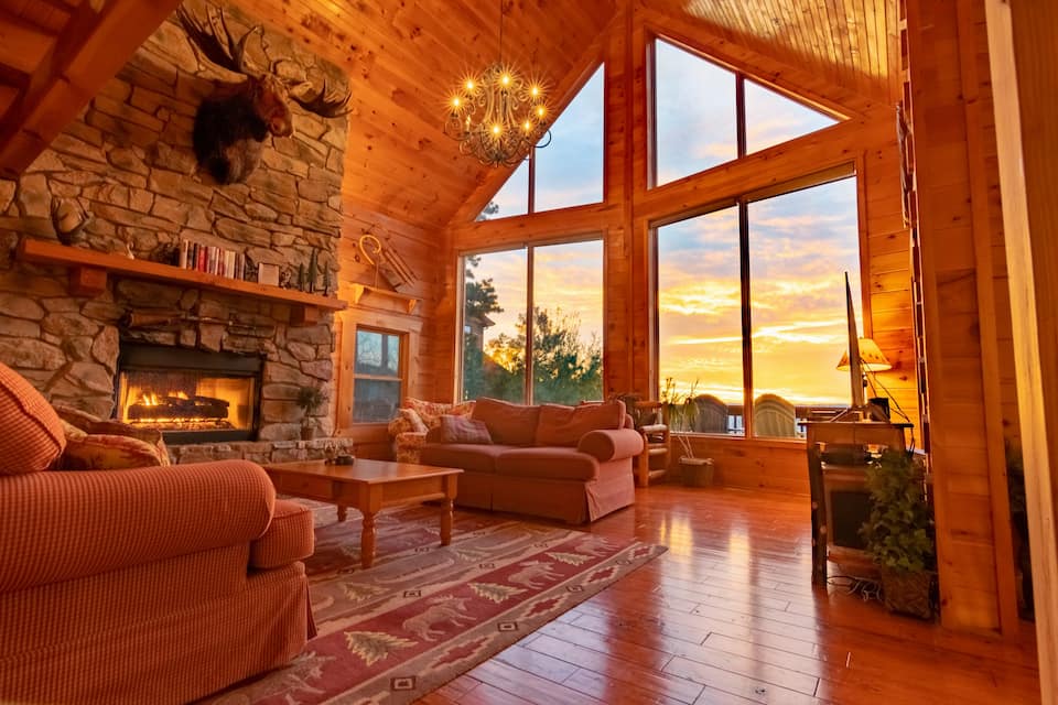 Living space inn log cabin with large windows showcasing sunset