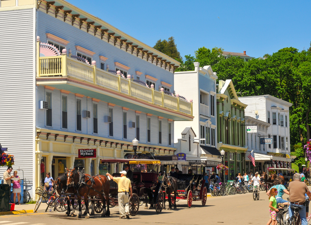 A street and horse drawn carriages on Mackinac Island one the small towns in Michigan great for a break