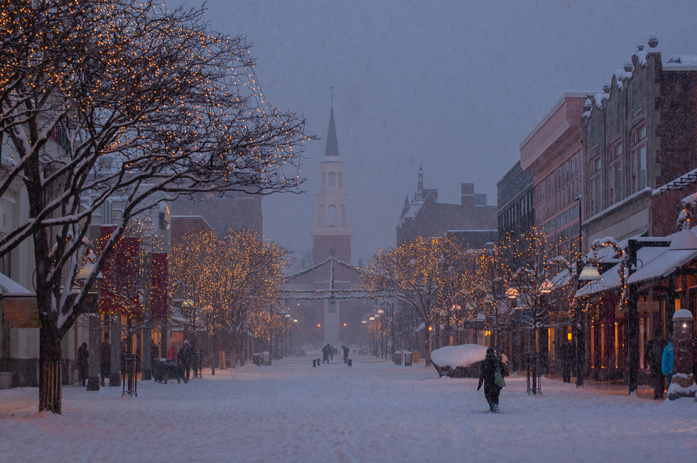 Snowfall on Church street a street lined with trees with a church in the background in Burlington