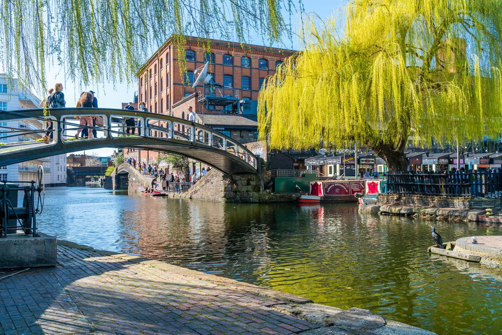 people walking on a bridge over a canal surrounded by eateries things to do in camden