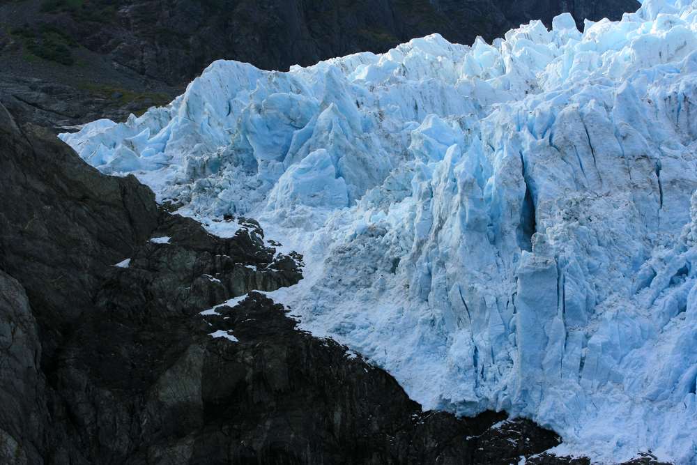 close up of glacier with black rocks and blue ice.