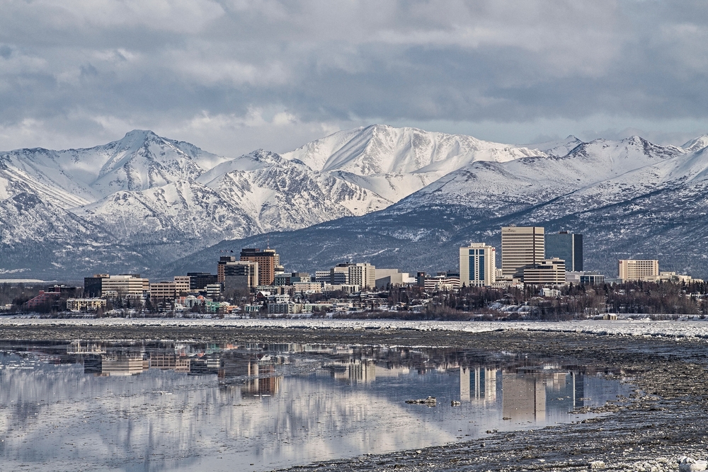 city reflection in water with snowy mountains behind