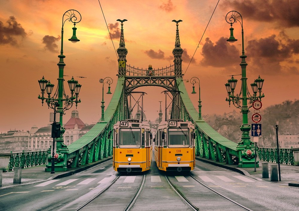 yellow trams on a bridge traveling to budapest