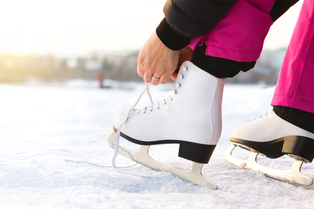 woman tyings her ice skates on snow