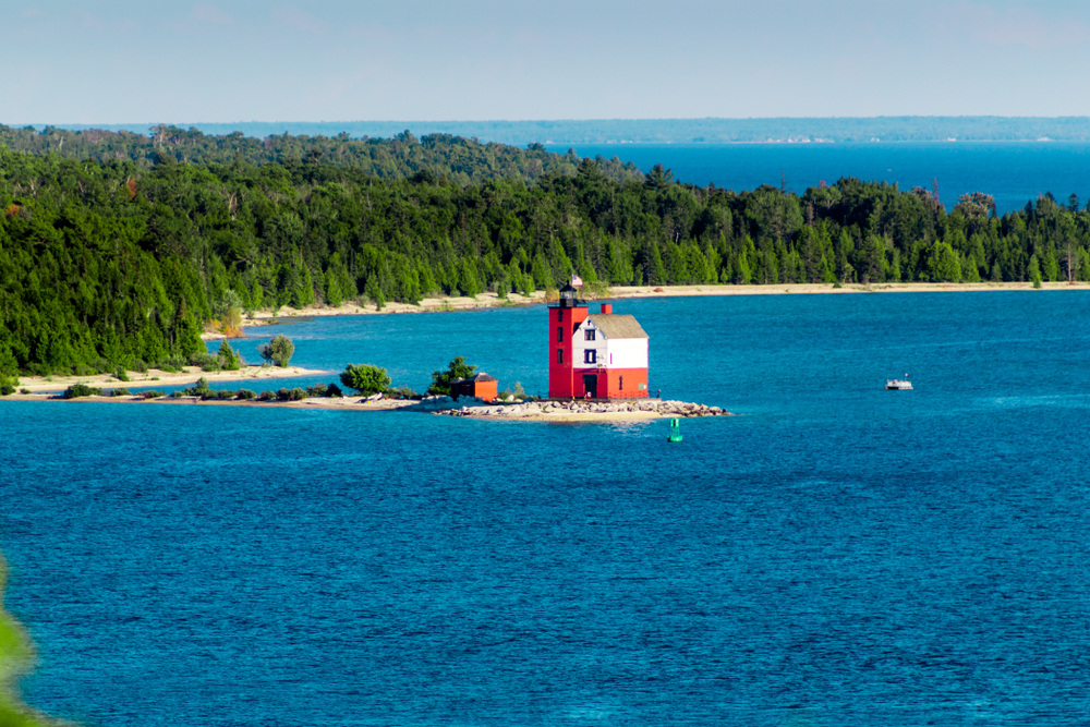 red lighthouse in the ocean beside trees