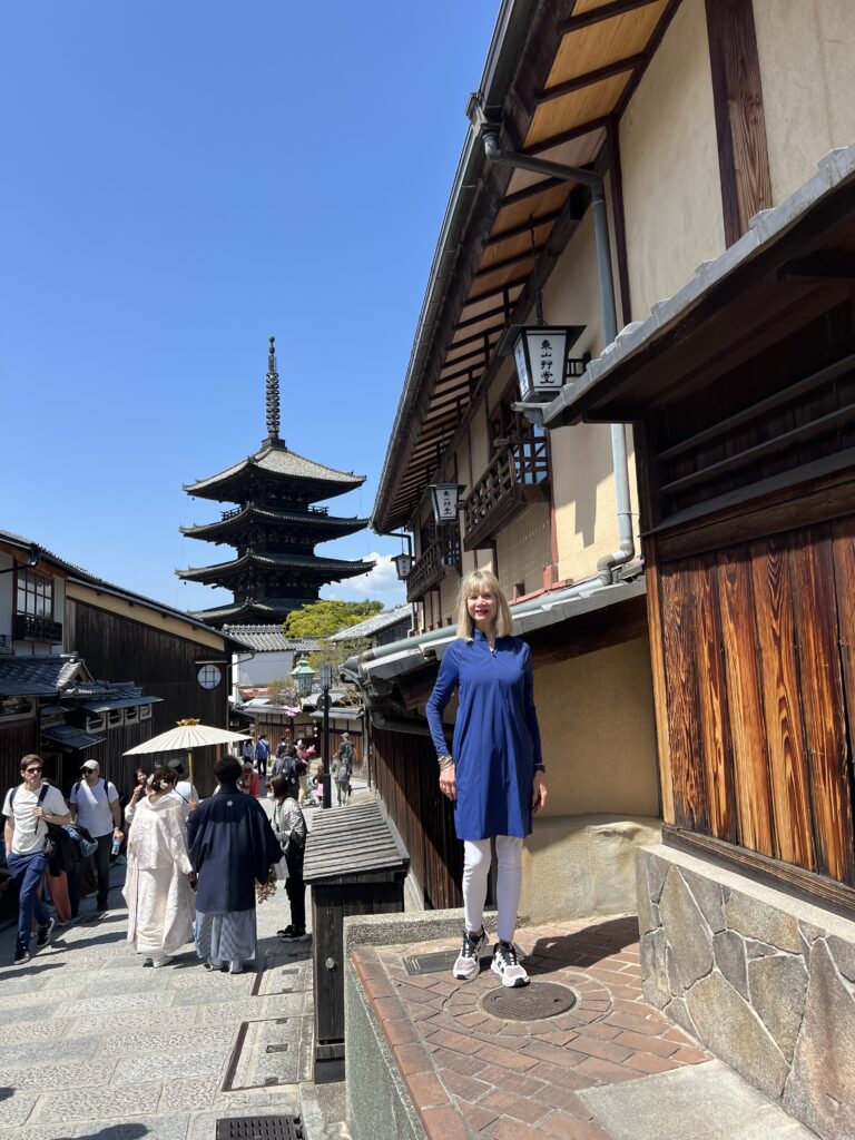 a lady in blue standing in q street with pagoda in the background