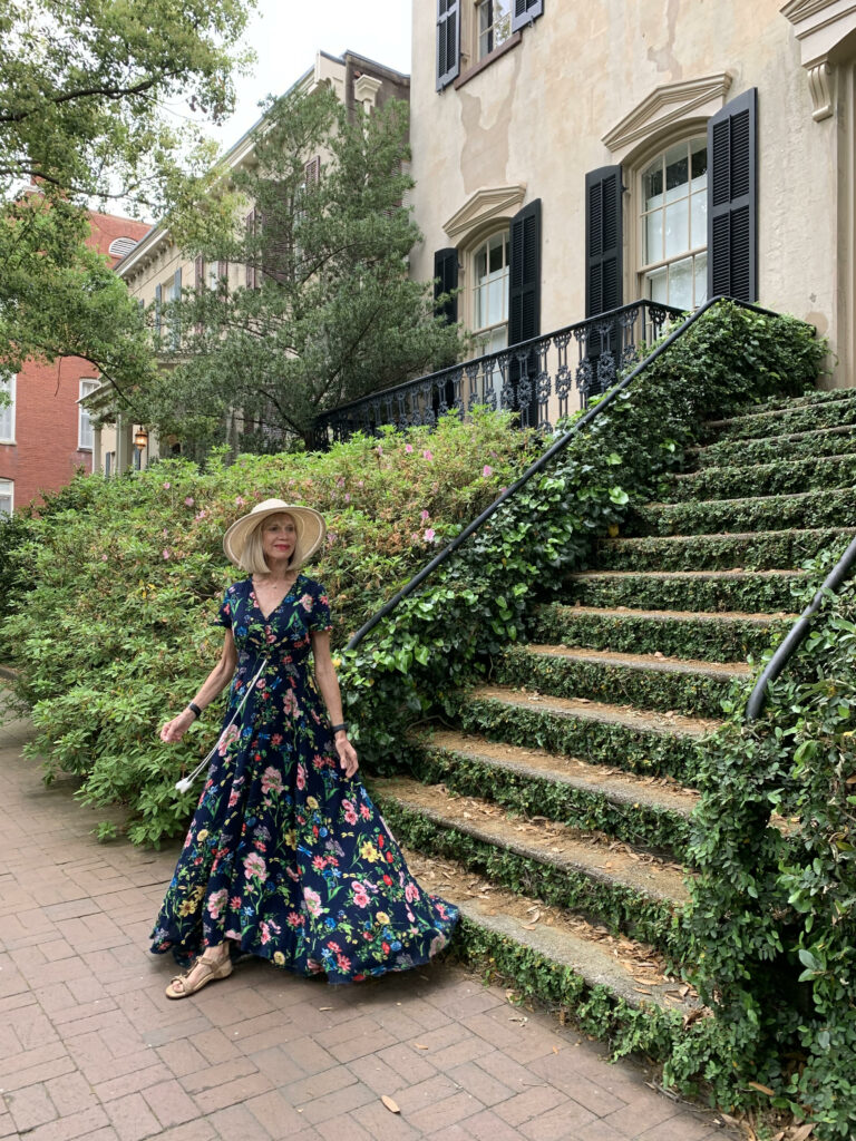 woman in long dress climbing down the stairs covered in greenery