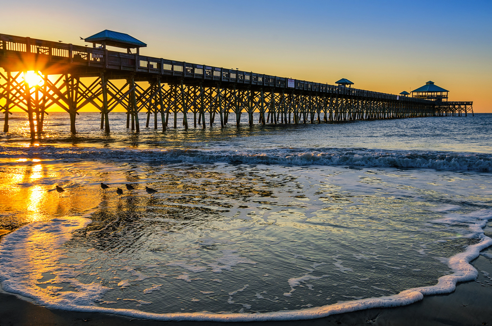 tide at a beach with a bridge during sunset