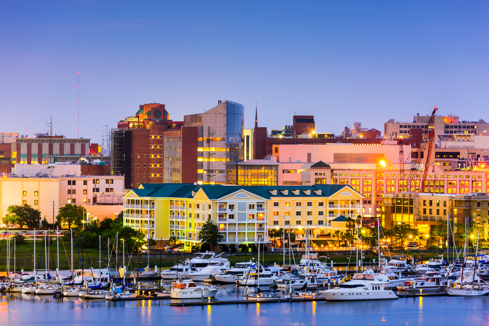 boats in the harbor with buildings lit up in the backdrop christmas in charleston