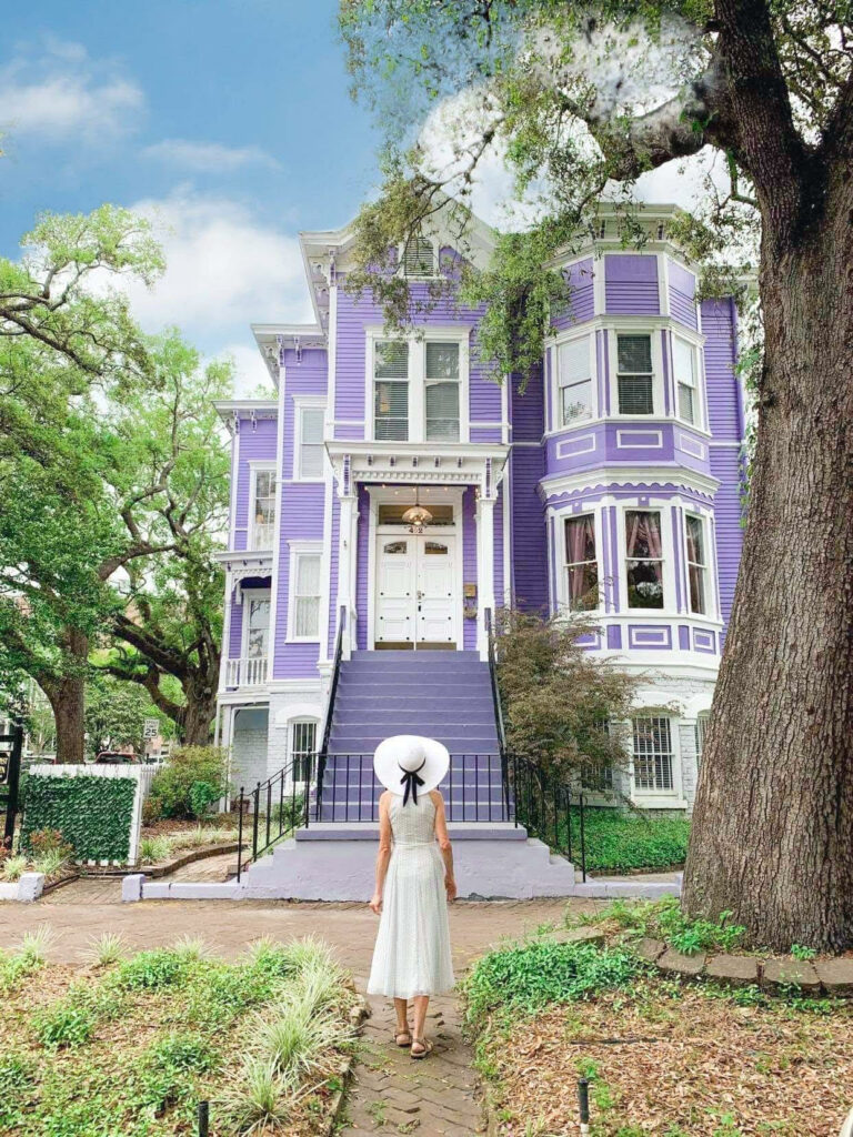 woman in white dress standing in front of a lavender house