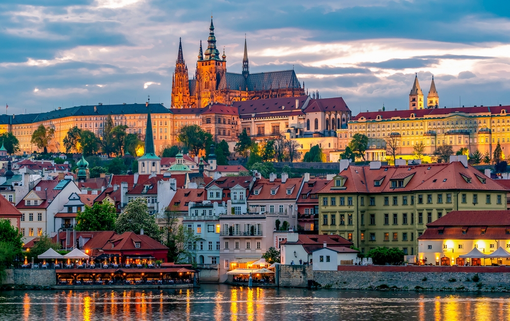 huge castle surrounded by colorful buildings and river 