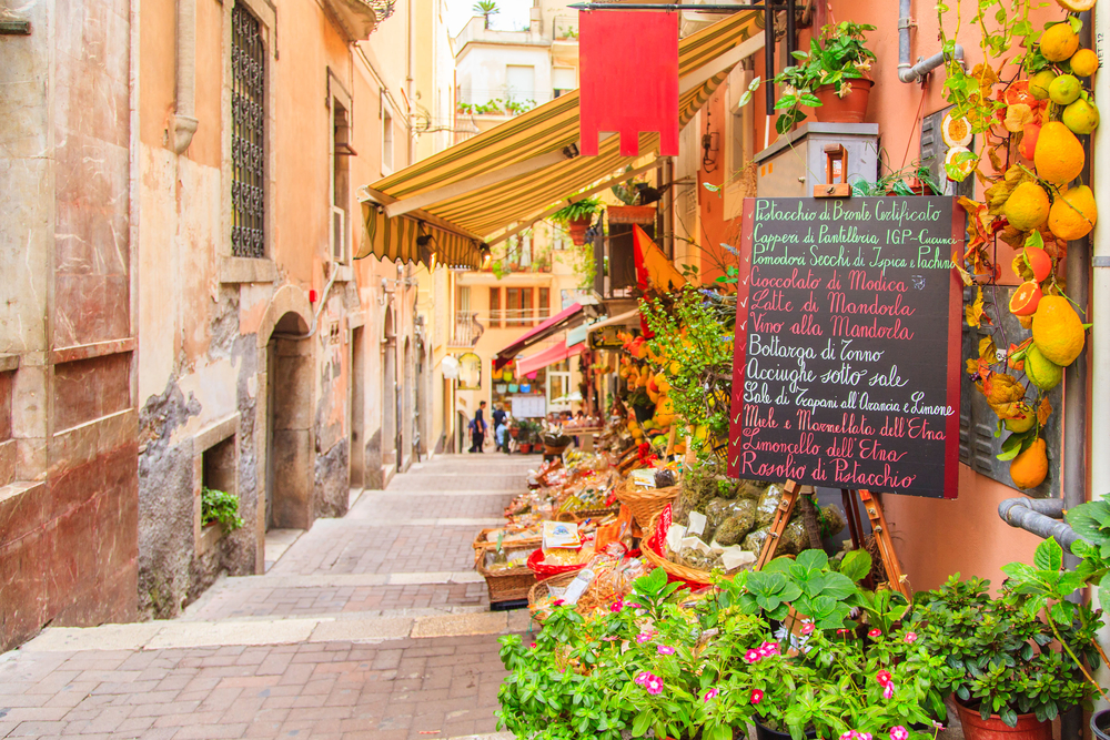 small colorful street lined with flowers and fruits romantic cities in europe