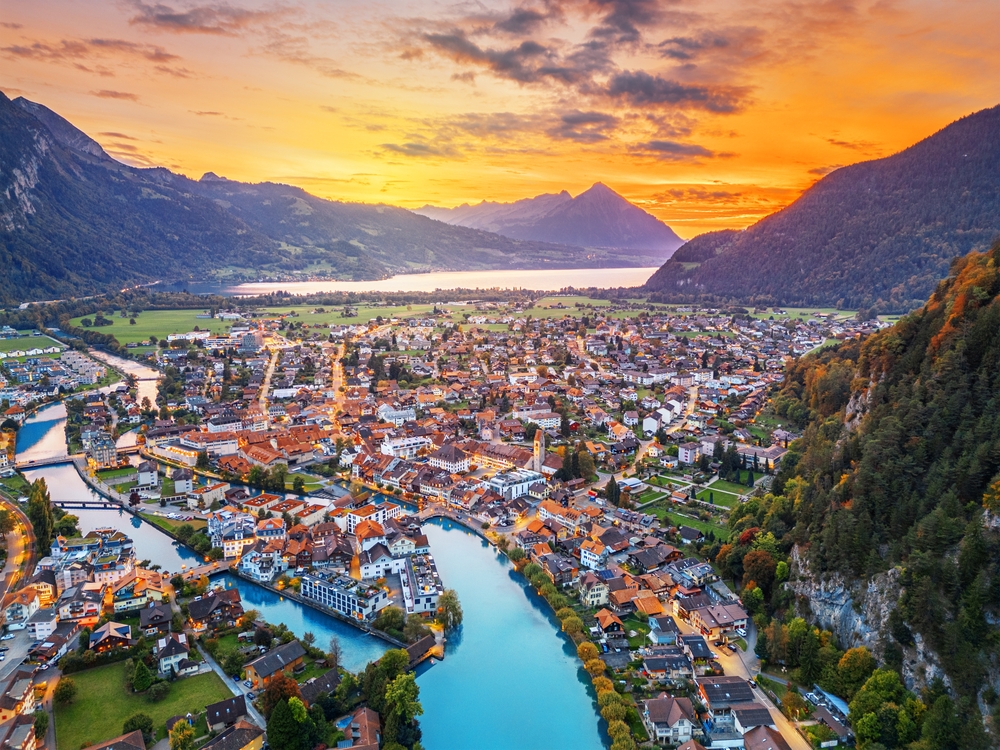 aerial view of a town surrounded by mountains as the sun sets