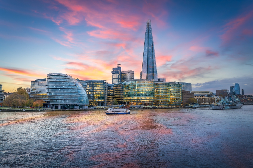 glass buildings including a skyscraper beside the river during sunset 