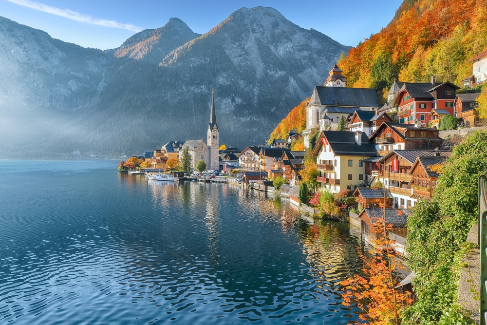 view of town beside lake surrounded by mountains europe vacation tips