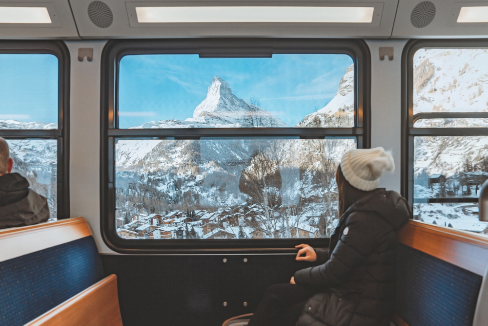 girl looking at the mountains from the window of a train