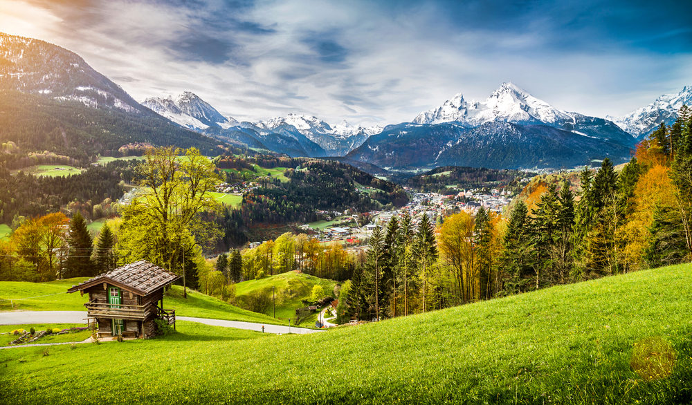 mountain town with lots of trees and snow peak mountains in the distance