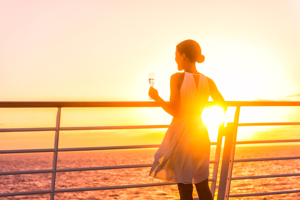 woman holding a champagne glass enjoying the sunset on cruise