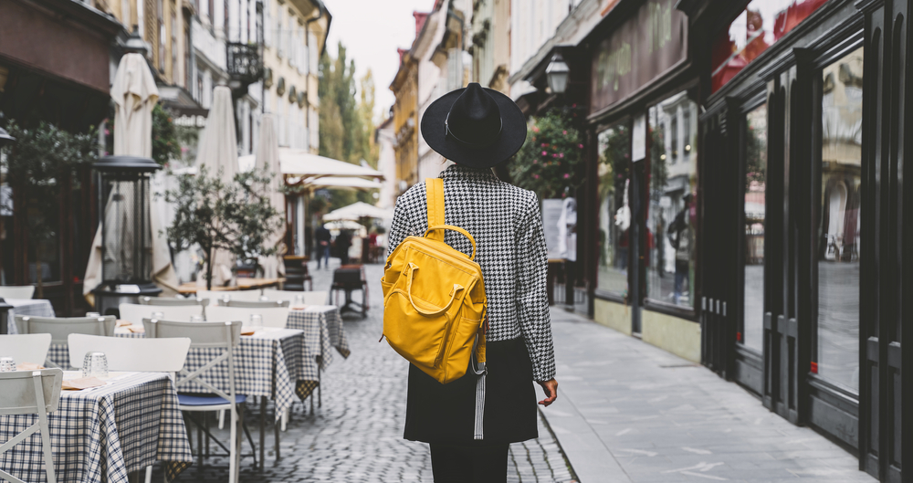 woman wearing black hat and outfit with checked jacket and yellow daypack paris in winter