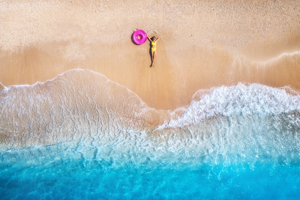 aerial view of a girl lying on the beach traveling to the maldives
