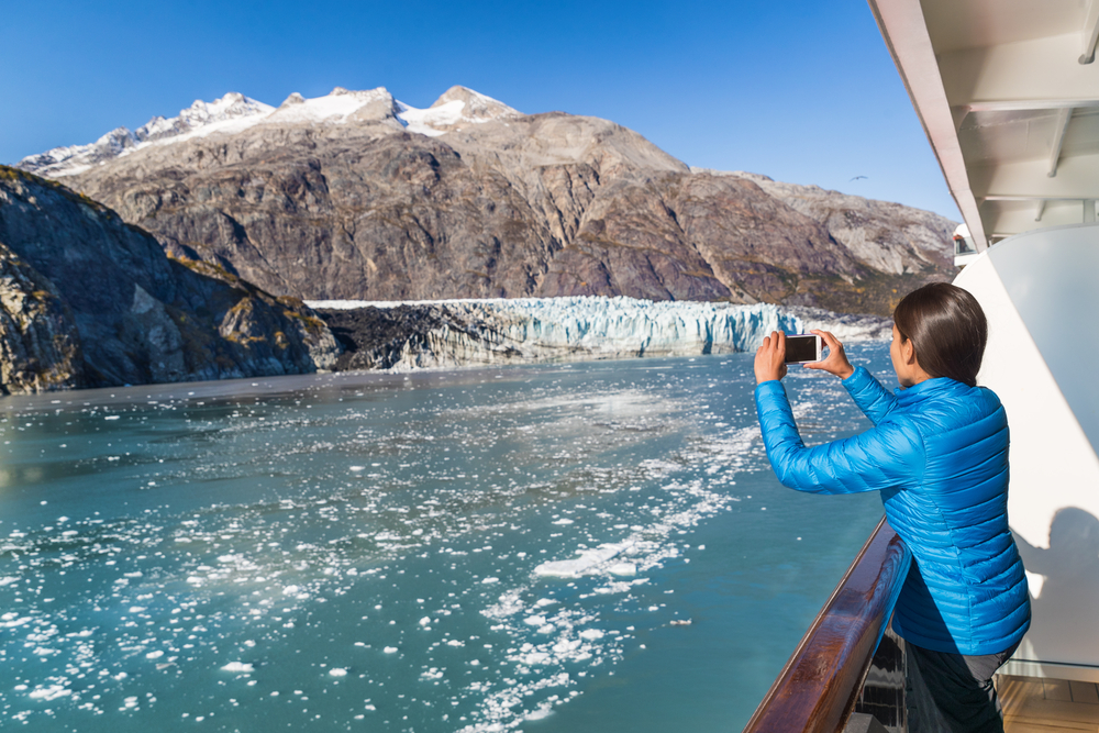 girl taking a photo of a glacier from a cruise ship alaska cruise outfits for july