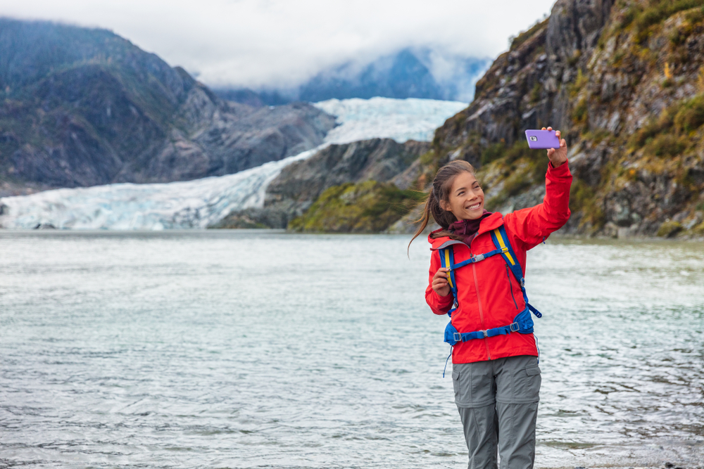 woman taking selfie in front of a glacier alaska cruise outfits for july