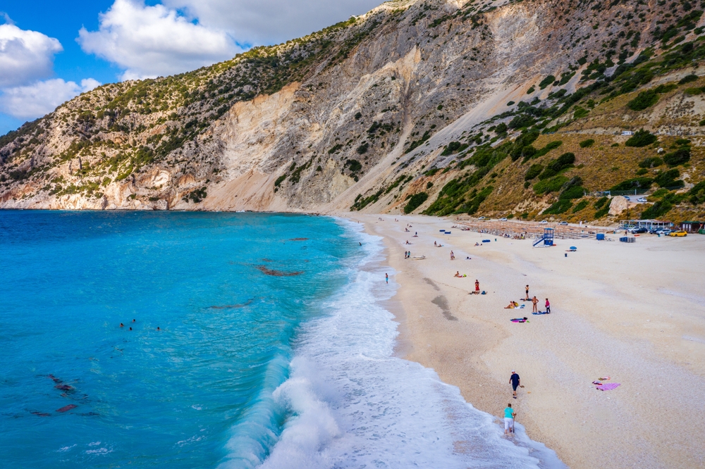people on the beach traveling to greece