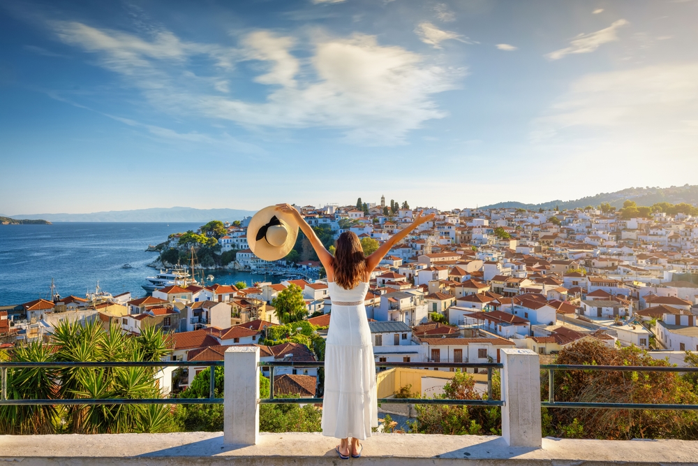 woman in front of a view of the charming houses with ocean on one side traveling to greece