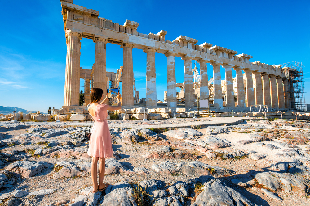 young woman photographing the ruins of a historical building traveling to athens