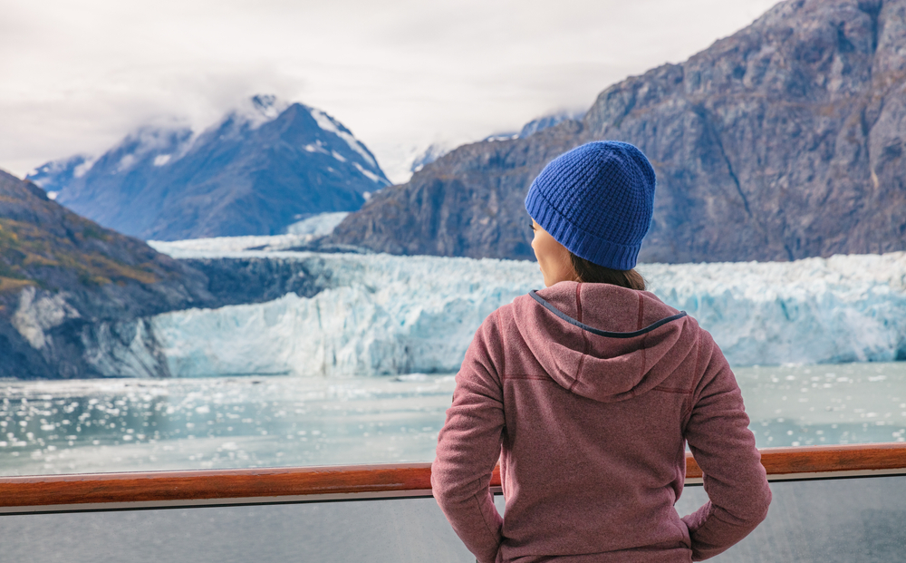 woman in pink fleece and blue beanie looking at the glacier alaska cruise outfits for august