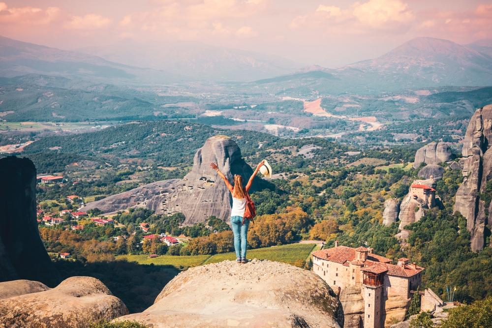 girl standing on a cliff with views of the valley and nearby rocks