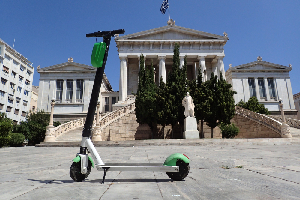 e scooter in front of a white greek building with greece flag