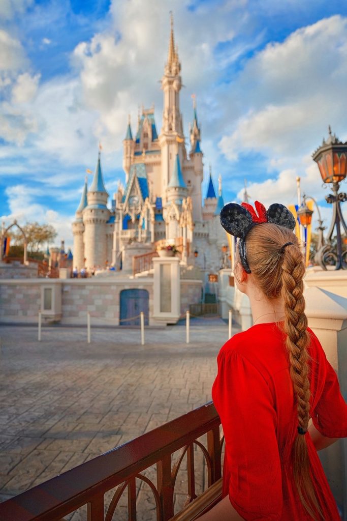 girl in red standing looking at the disney castle