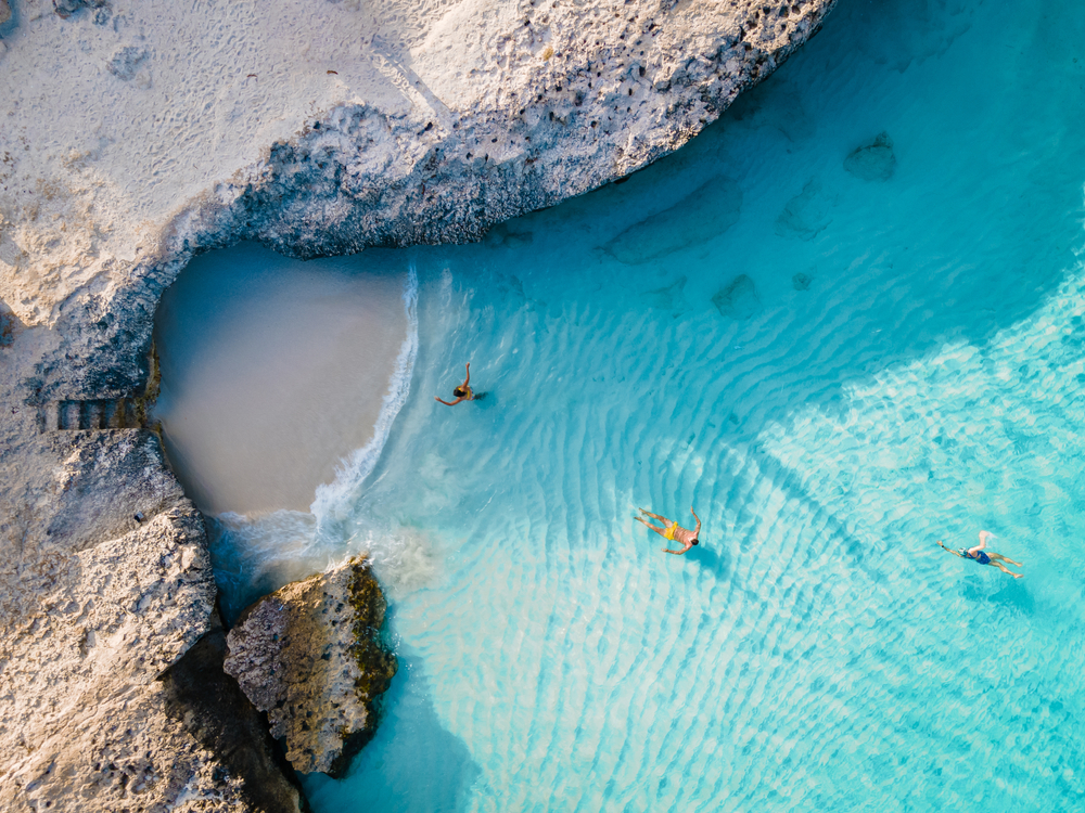 aerial view of a beach with cliffs and people around warm weather getaways