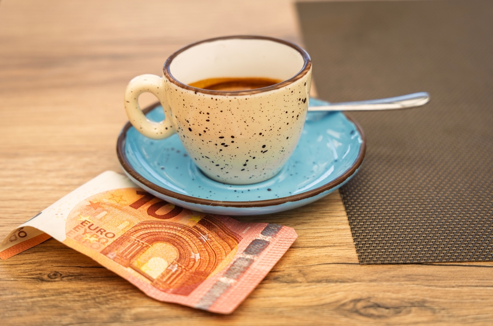 a cup of espresso on a rustic saucer with 10 euro note underneath it