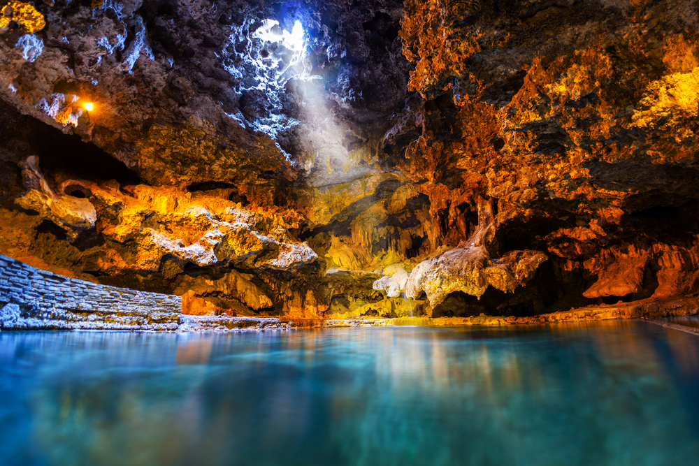 beam of light shining through an opening of a cave filled with water things to do in banff