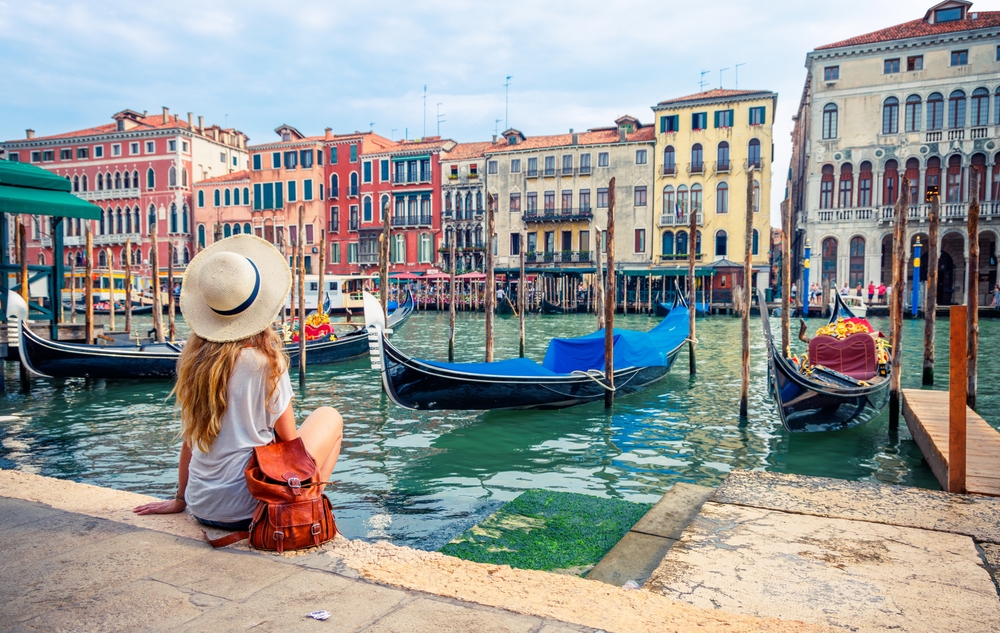 girl sitting on a harbour enjoying the city views and boat view traveling to italy