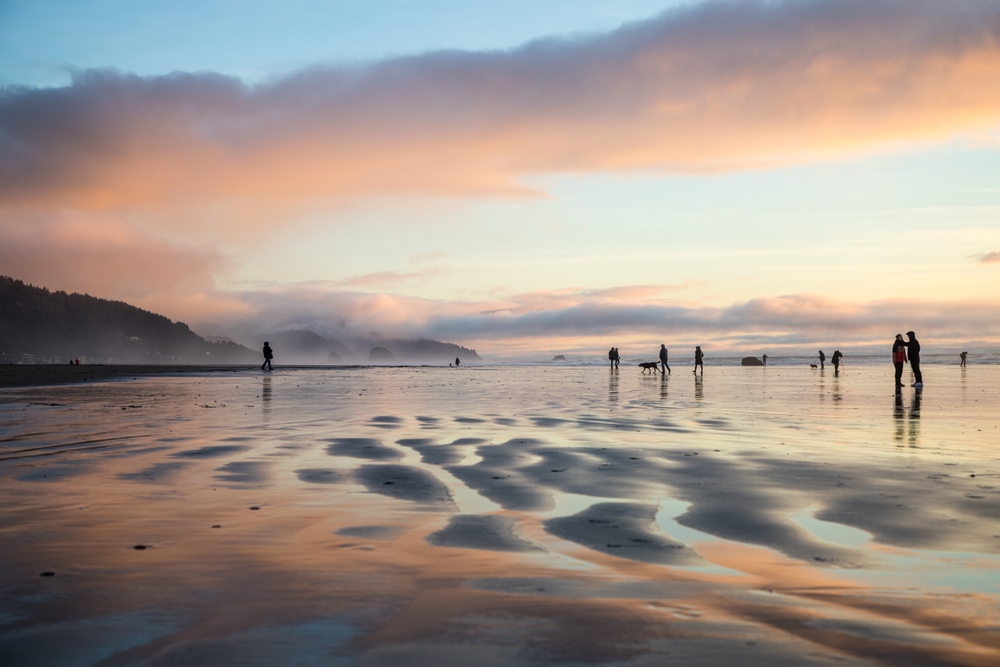 beach reflecting the sunset colors with people standing on it