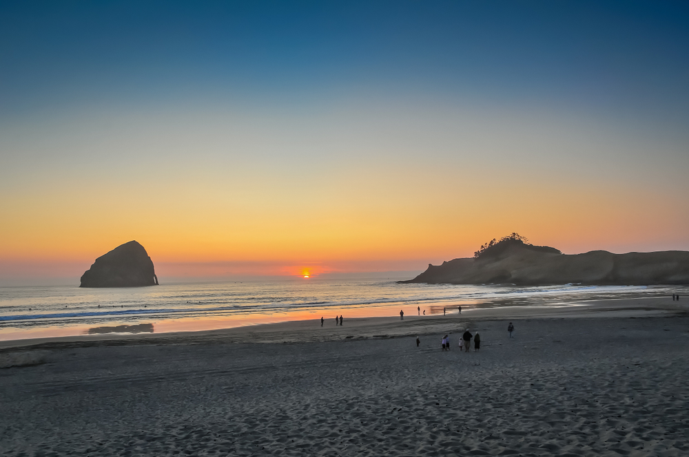 sun setting in the ocean visible from the beach oregon coast getaways