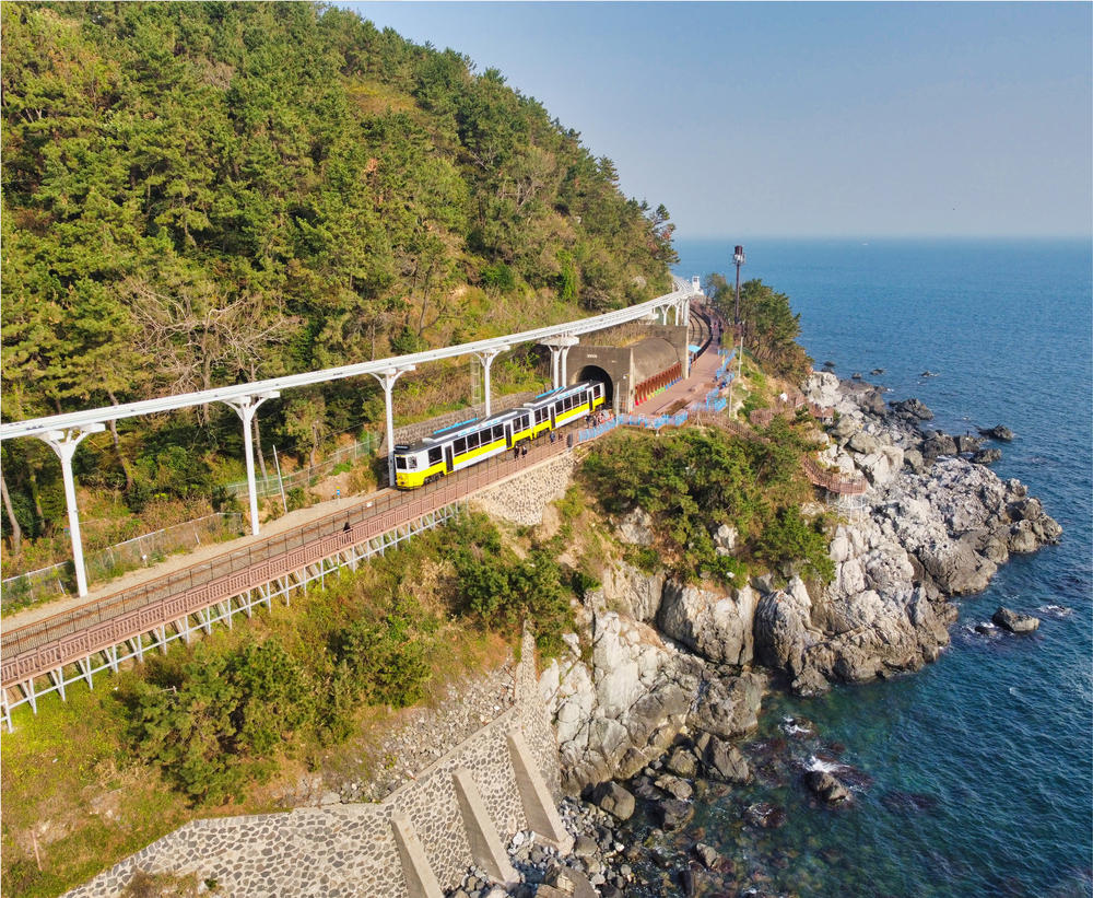 aerial view of a colorful train getting out of a tunnel Haeundae blueline park