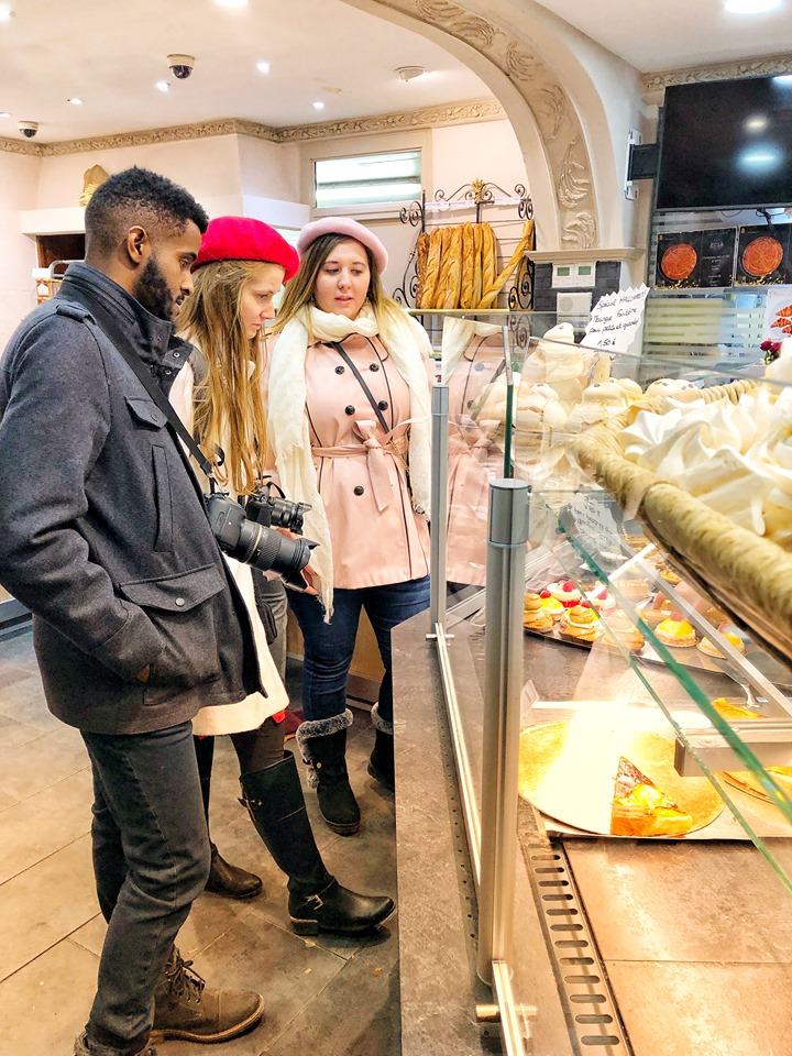 Two young, Caucasian women and one black man looking at a variety of Paris pastries during 2 days in Paris.