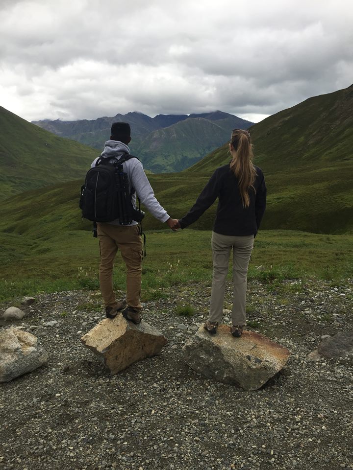 Young couple holding hands and overlooking Hatcher Pass on a cloudy day.