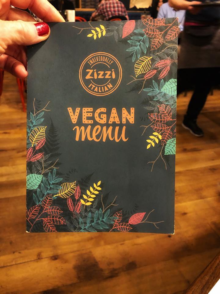 Gray vegan menu with wooden floor  in background.