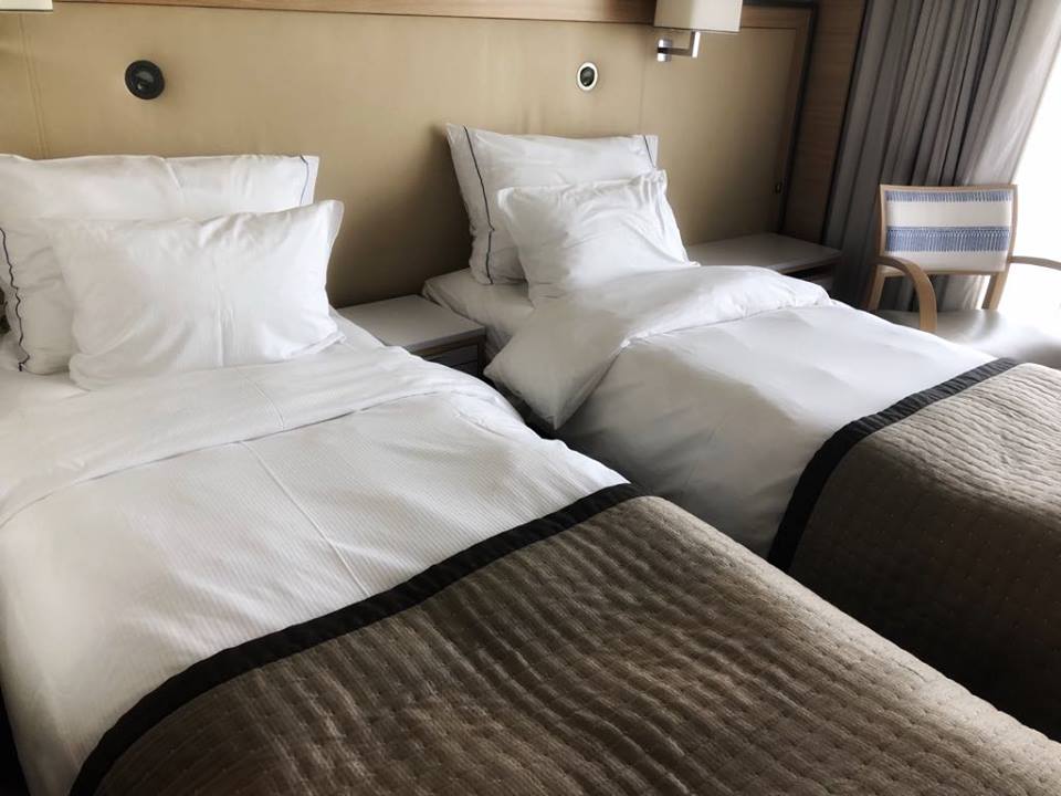 two twin beds with brown coverlet and chair on the right