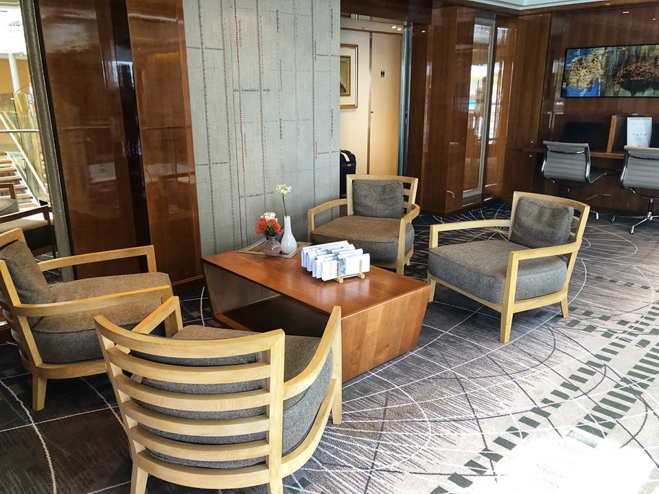 group of chairs around wooden table with papers folded on top of it.