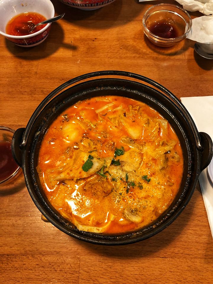 Black bowl containing red soup with vegetables