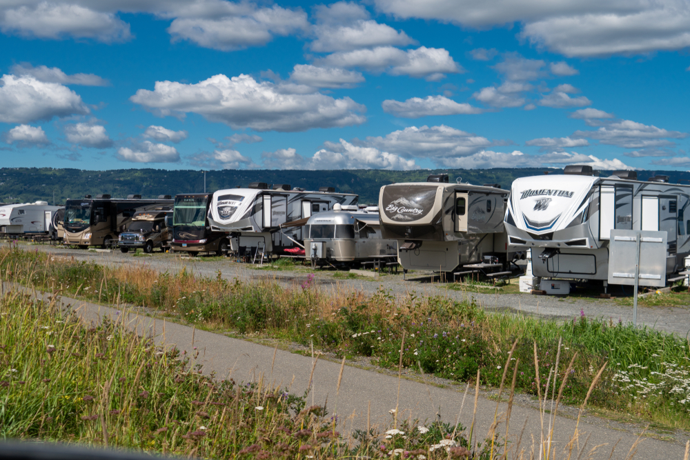 things to do in Homer Alaska include camping along the Spit
Colorful trailers and RVs parked along side of road with green overgrown grass in foreground.